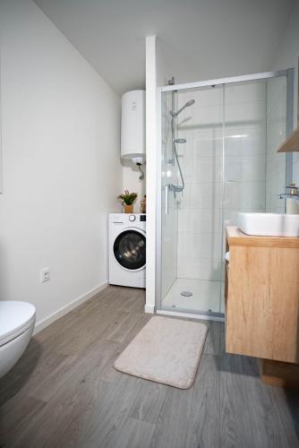 a bathroom with a shower and a sink and a washing machine at AC Ivona - Mobile home AURORA Vodice in Vodice