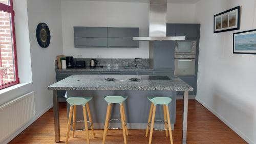 a kitchen with a island with bar stools at Les 3 conserveries in Le Crotoy