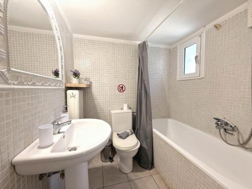 a bathroom with a sink and a toilet and a tub at Elena's 3BR Maisonette with Garden & Pool in Nea Plagia