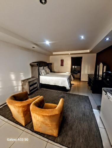 a bedroom with a bed and two couches in it at Aquamarine Guesthouse in Morula Sun