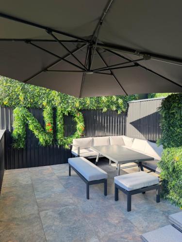 a patio with a table and benches and an umbrella at Nuit D Or LoveRoom in Bellegarde-sur-Valserine