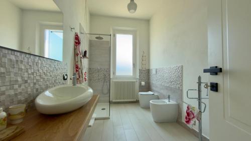 a white bathroom with a sink and a toilet at Appartamento Le Crugnole in Montepulciano