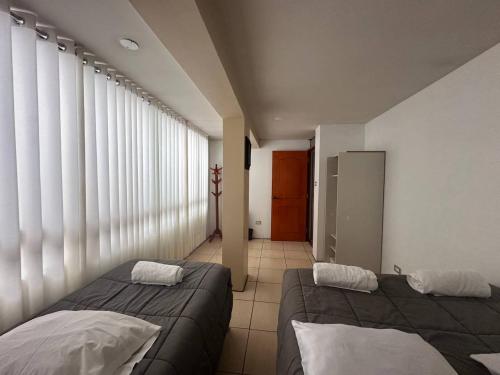 a room with two beds in a room with large windows at Domi ApartHotel , first floor and duplex in Cusco