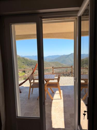 a sliding glass door with a table and chair on a balcony at Casa Punta Di Vista in Venaco