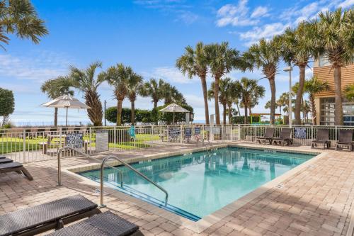 a swimming pool with chairs and palm trees at Breakers Resort Hotel in Myrtle Beach