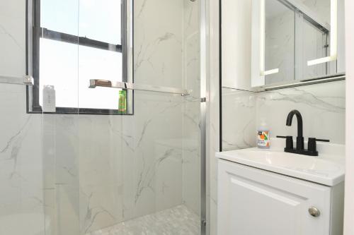 a white bathroom with a shower and a sink at Chic 2BR Stay-Steps From Central Park in New York
