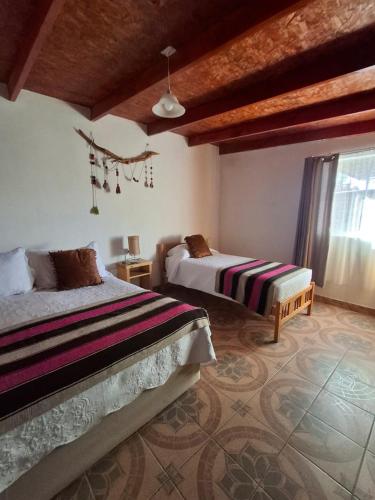 a bedroom with two beds and a large window at Cabañas el Chañar in San Pedro de Atacama