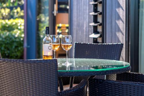 two glasses of wine sitting on a table on a patio at Moa 30 Runga - Coast & Country in Oneroa