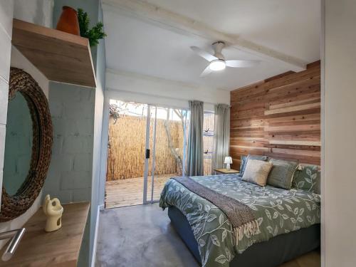 a bedroom with a bed and a wooden wall at Ocean Whisper Beach Villas in Jeffreys Bay