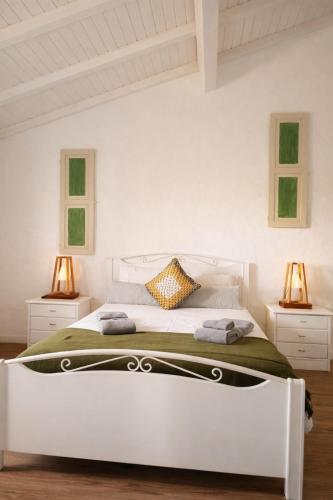 a white bedroom with a white bed with two lamps at Monte da Rocha 3 Marias in São Bartolomeu da Serra