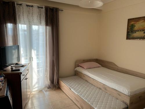 a small bedroom with a bed and a window at petite apartment in Asprovalta