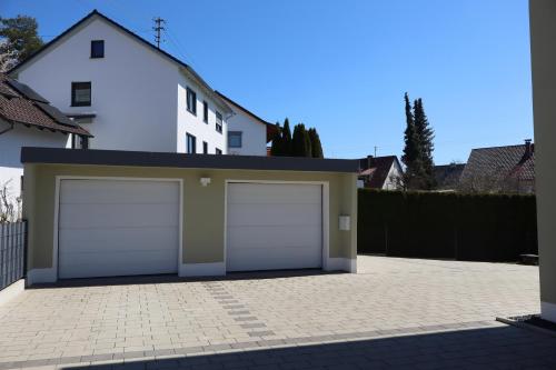 a white house with two garage doors in a driveway at Ferienhaus Ferati - Modernes Neubau-Haus & nahe Legoland in Günzburg