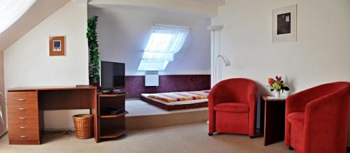 a living room with a bed and two red chairs at Pension Habermannova Vila in Bludov