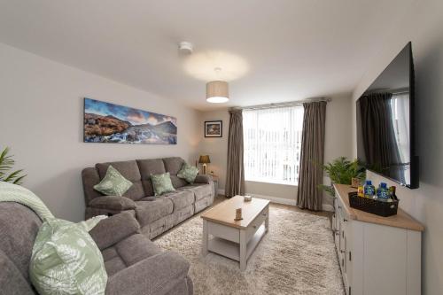 a living room with a couch and a flat screen tv at Banbridge Central Stay in Banbridge