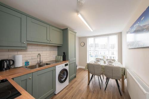 a kitchen with green cabinets and a table with chairs at Banbridge Central Stay in Banbridge