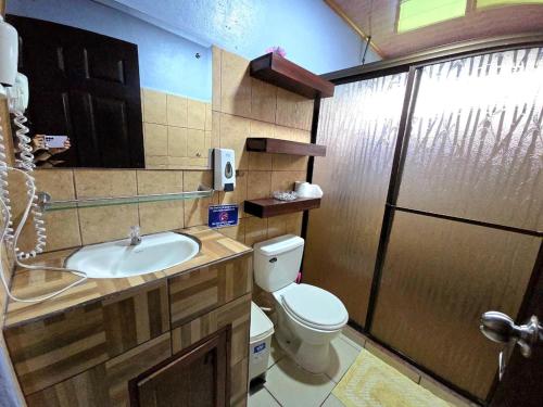 a bathroom with a toilet and a sink and a shower at La Martha in Sarapiquí
