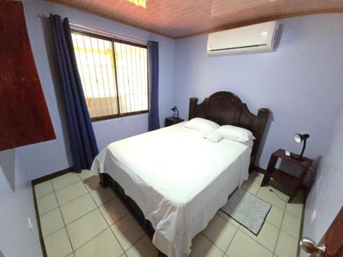 a bedroom with a white bed and a window at La Martha in Sarapiquí