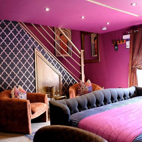 a bedroom with purple walls and chairs and a bed at St Hildas Boutique in Hinderwell