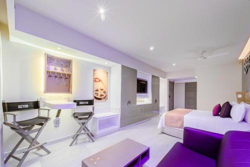 a hotel room with a bed and a desk and a couch at Planet Hollywood Cancun by Royalton, An Autograph Collection All-Inclusive Resort in Cancún