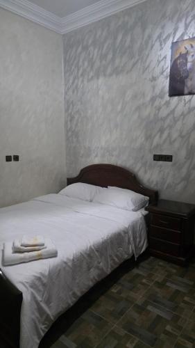 a bedroom with a white bed with a wooden headboard at Maison marhaba2 app2 in Inezgane