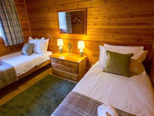 a bedroom with two beds in a log cabin at Tormore Cabin in Carrbridge