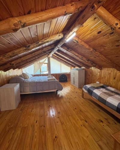 a large attic room with two beds and wooden floors at Cielo Azul 2 in Villa Pehuenia