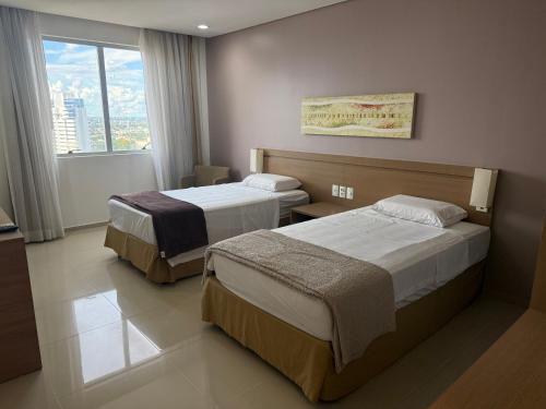 a hotel room with two beds and a window at Flat no Hotel Blue Tree in Manaus