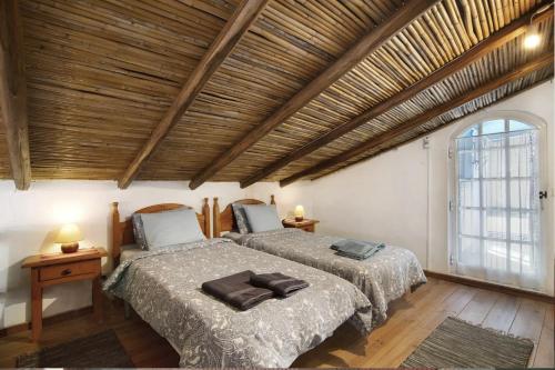 a bedroom with two beds and a wooden ceiling at Casa Delfim - Casas Azul&Verde in Alte