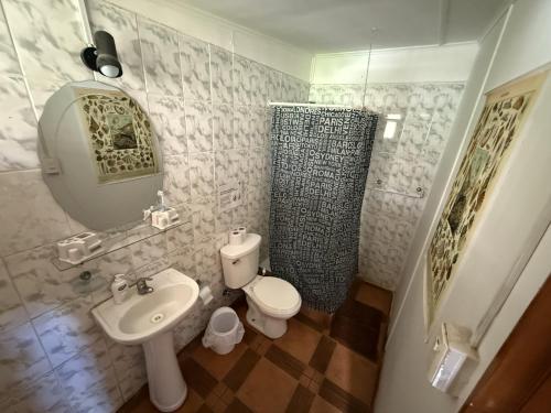 a bathroom with a sink and a toilet and a mirror at Hostal Vaihere in Hanga Roa