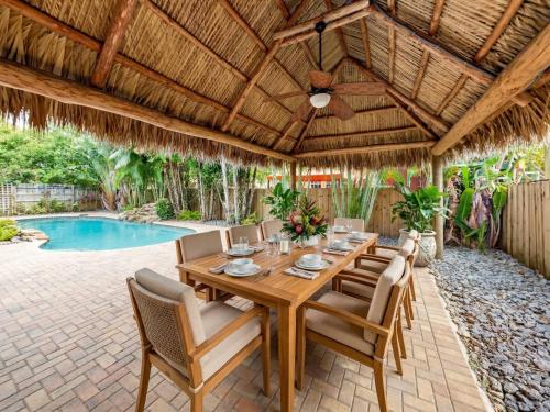 an outdoor dining room with a wooden table and chairs at Hidden Gem Vacation Villa w Private Pool & TikiHut in Fort Lauderdale