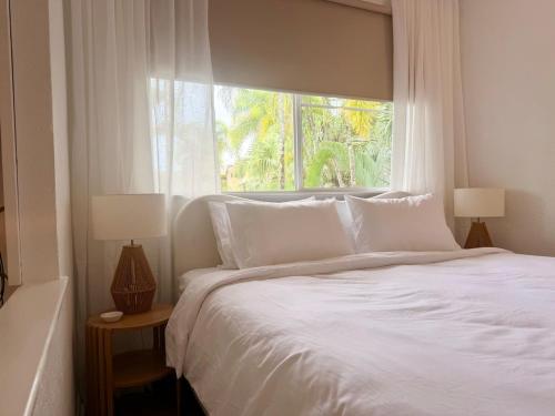 a bedroom with a white bed with a window at Tropic Sands Coastal Escape in Port Douglas