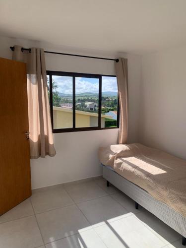 a small bedroom with a bed and a window at Casa Ville Perignon in Gravatá
