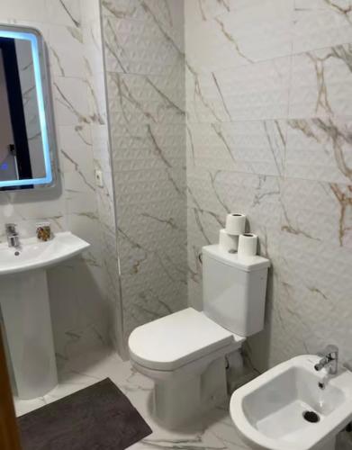 a white bathroom with a toilet and a sink at Asilah Ocean View Residence in Asilah