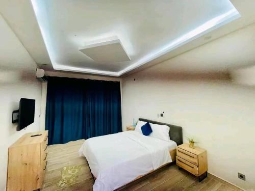 a bedroom with a white bed and a blue curtain at villa rach in Assinie