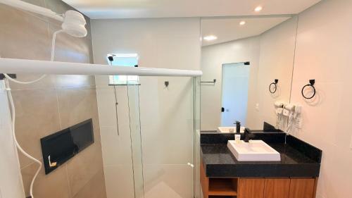 a bathroom with a shower and a sink and a television at Style and lightness 300m from the beach in Salvador