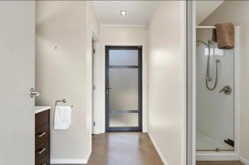 a bathroom with a walk in shower and a glass door at Relaxed Getaway in Mangawhai