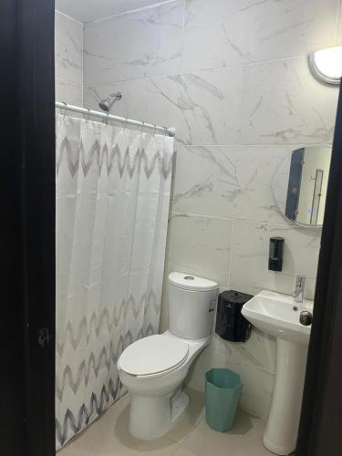 a white bathroom with a toilet and a sink at Hotel Urban Tacana in Tapachula
