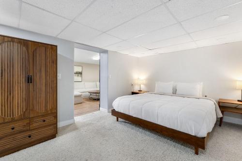 a white bedroom with a large bed and a wooden cabinet at Mt Rushmore Duplex in Rapid City
