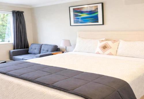 a bedroom with a large bed and a blue chair at Stylish Tawa Retreat in Wellington