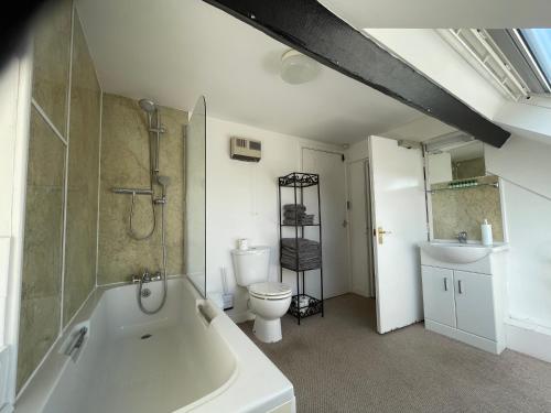 a bathroom with a tub and a toilet and a sink at Durbeyfield in West Bay