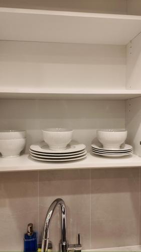 a kitchen shelf with bowls and plates on it at Central Luxe in Surrey