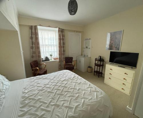 a bedroom with a bed and a flat screen tv at Durbeyfield in West Bay