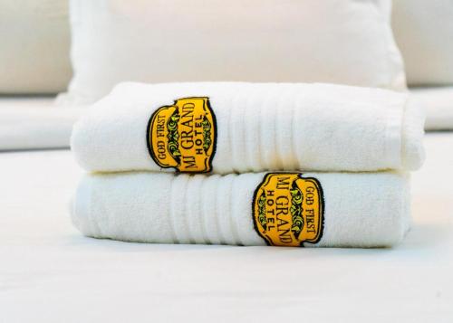 a stack of white towels with yellow stickers on them at MJ Grand Hotel in East Legon