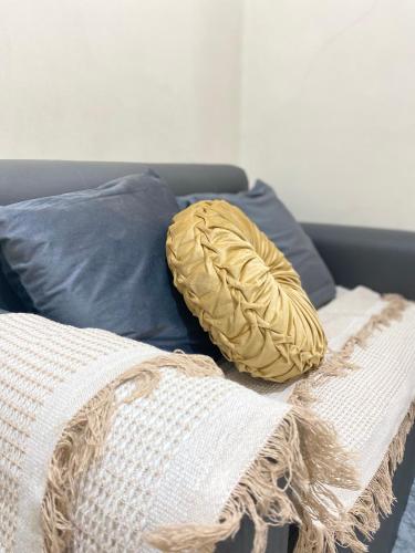 a yellow pillow on a bed with blue pillows at MGs Dwell - Baguio Transient at Moldex Residences in Baguio