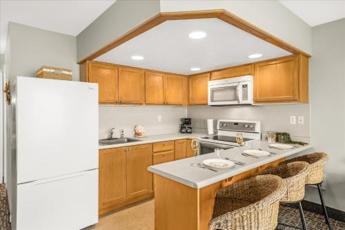 a kitchen with wooden cabinets and a white refrigerator at Oceanfront Family Suite - Full Kitchen - Beautiful Views and Pool & Hot Tub Access in Lincoln City