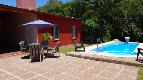 a patio with chairs and an umbrella next to a pool at Cabaña LA SOÑADA in Villa Anizacate