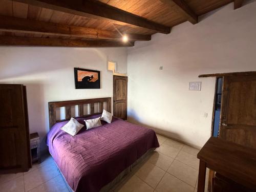 a bedroom with a bed with a purple bedspread at Hotel del Pozo in San Sebastián del Oeste