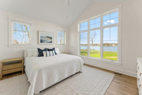 a white bedroom with a bed and large windows at Bay Dreaming in Montross