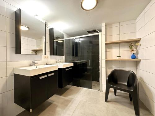 a bathroom with a black chair and a sink at Le Congo in Ochamps