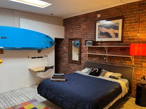 a bedroom with a bed and a brick wall at beachside loft warehouse artists retreat in Edithvale